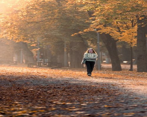 A serene person enjoying a mindful walk through a sunny public park in Bucharest during morning hours