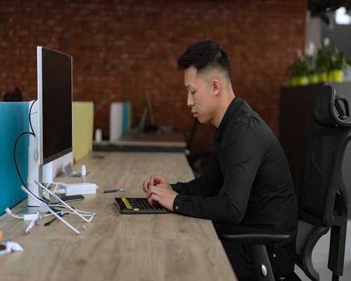 A side view of a person maintaining a comfortable and correct posture at a clean wooden office desk